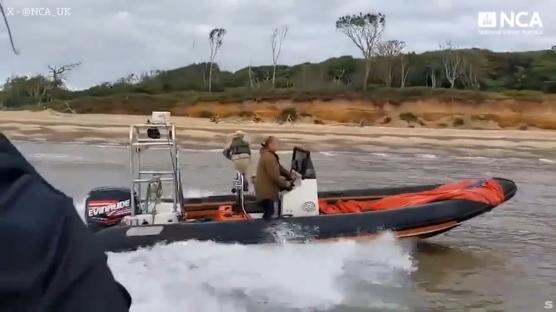 Screenshot of a rigid-hulled inflatable boat speeding across the water near a sandy beach.