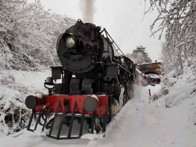 The Polar Express train pushing through snow on the tracks.