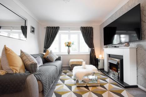 Interior view of a small living room with gray sofa, fireplace, and flat-screen TV.