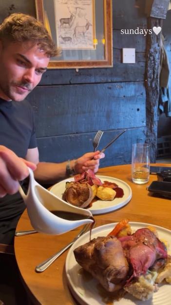 A man pouring gravy from a boat onto a plate of roast dinner.