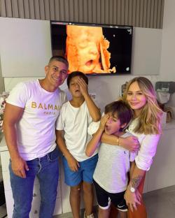 Family with two sons looking at a 3D ultrasound of their baby.