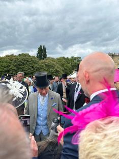 King Charles III shaking hands with a guest at a garden party.