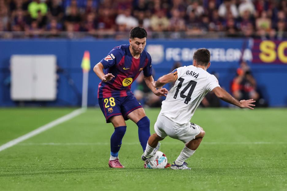 Roony Bardghji of FC Barcelona and Jose Gaya of Valencia CF compete for the ball.