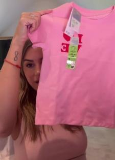 Woman holding up a pink children's t-shirt that says "I LOVE" on it.