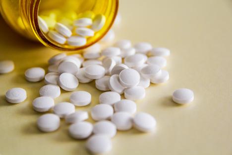 White pills spilling from a yellow pill bottle.