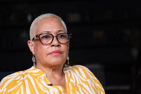 Close-up of a woman wearing glasses and a yellow and white striped shirt.