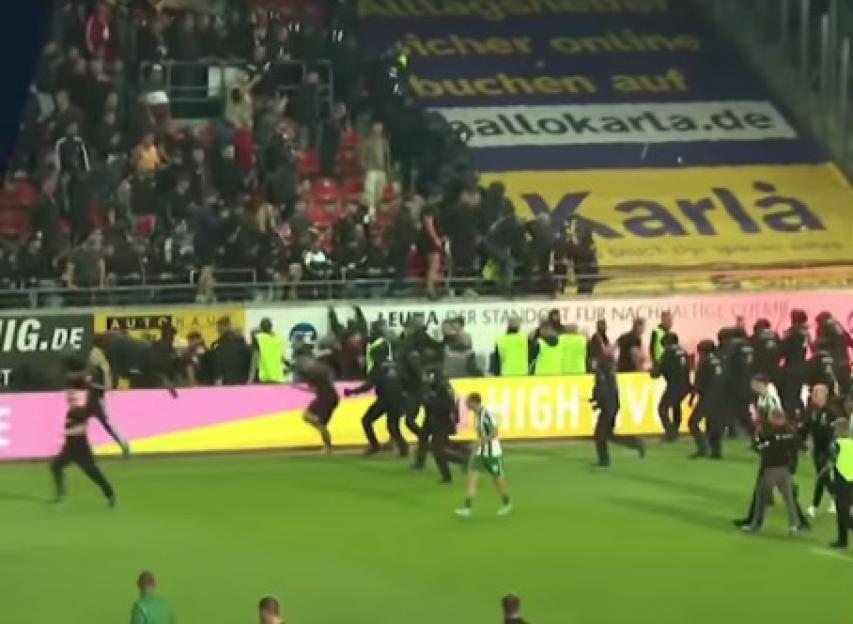 Stadium security personnel running onto the field to restrain fans.