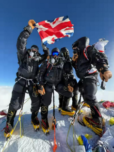 Climbers on a mountaintop holding a British flag.