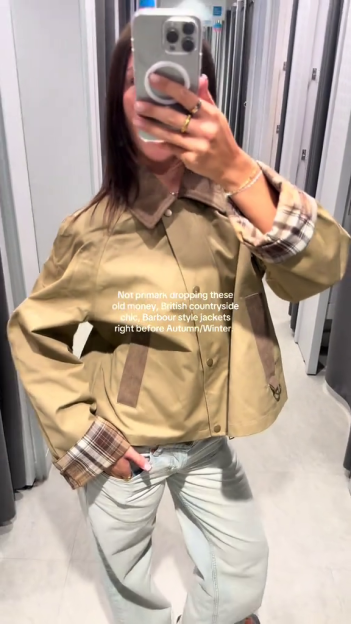 Person modeling a tan Barbour-style jacket in a Primark changing room.