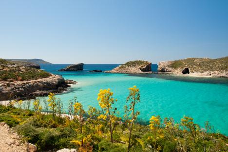 Turquoise water of the Blue Lagoon in Comino, Malta, with Cominotto islet in the background.