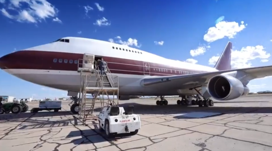 A large passenger plane on the tarmac with ground crew.