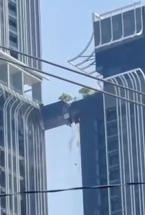 A father jumping across a collapsing walkway between two buildings during an earthquake.