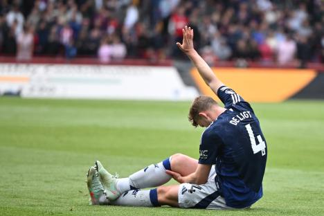 Matthijs de Ligt, #4 for Manchester United, sits on the field holding his leg.