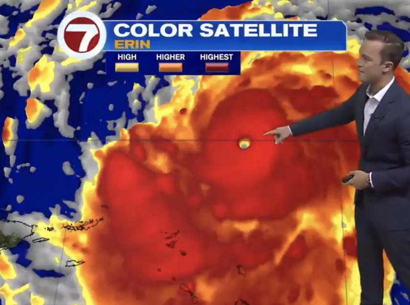 Weather reporter pointing at a color satellite image of Hurricane Erin.
