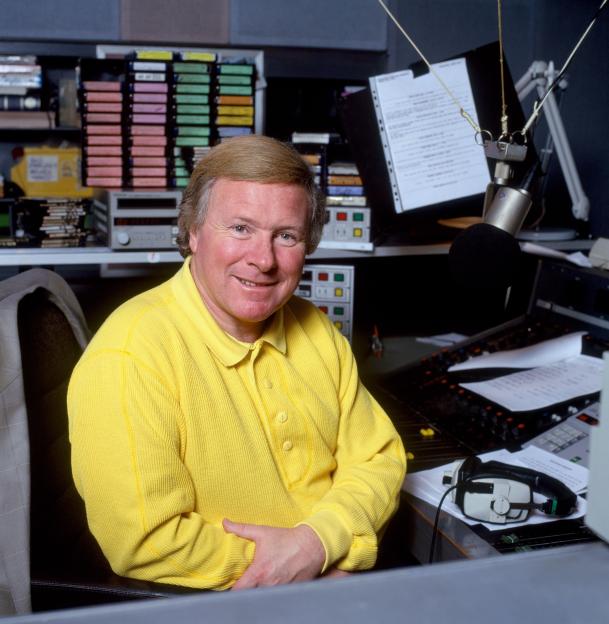 A man in a yellow shirt sitting in front of a microphone
