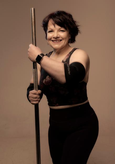 Smiling woman holding a barbell.
