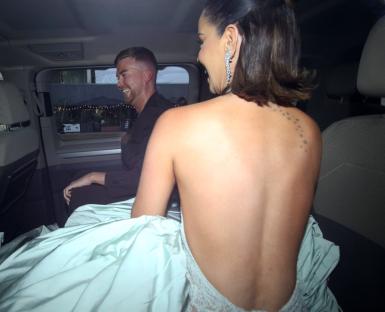 Woman in a backless gown and man leaving in a car.