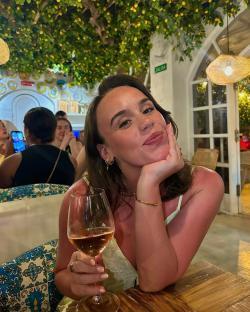 Woman smiling and holding a glass of wine in a restaurant.