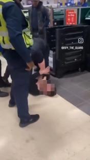 A security guard subdues a shoplifter in a Tesco store.