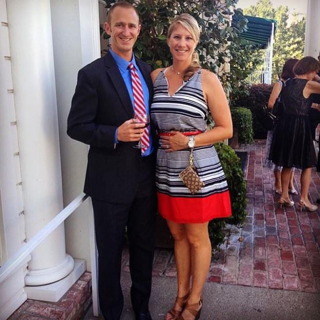 Couple at an event; man in suit holding a glass of wine.