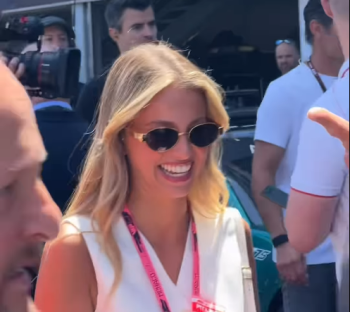 Smiling woman wearing sunglasses and a white top.