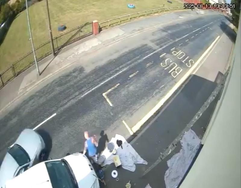 A painter is hit by a car at a bus stop.