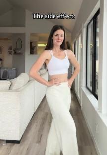 Woman in white crop top and pants, showcasing weight loss.