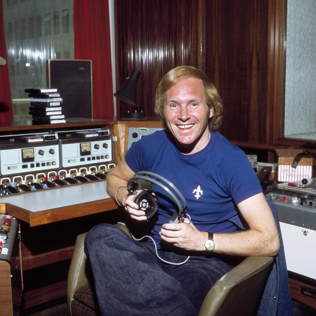 A man in a blue shirt holding headphones