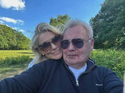 Couple smiling for a selfie outdoors.