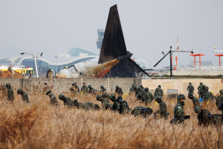 South Korean Army members searching a field near the wreckage of a Jeju Air Co. Flight 2216 plane at Muan International Airport.