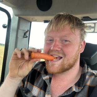 Man eating a carrot in a tractor.