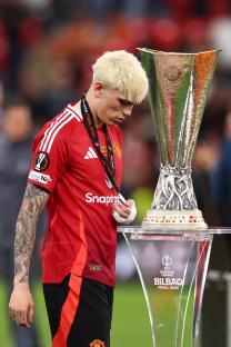 Alejandro Garnacho of Manchester United reacts next to the UEFA Europa League trophy.