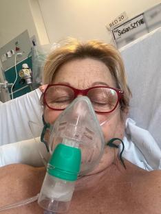 Woman in hospital bed wearing oxygen mask.