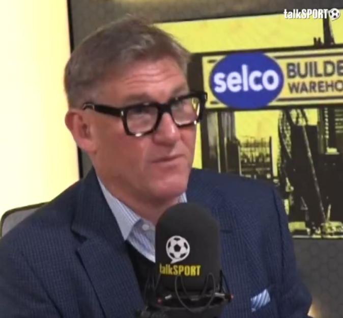 Simon Jordan wearing glasses and a suit, speaking into a talkSPORT microphone.