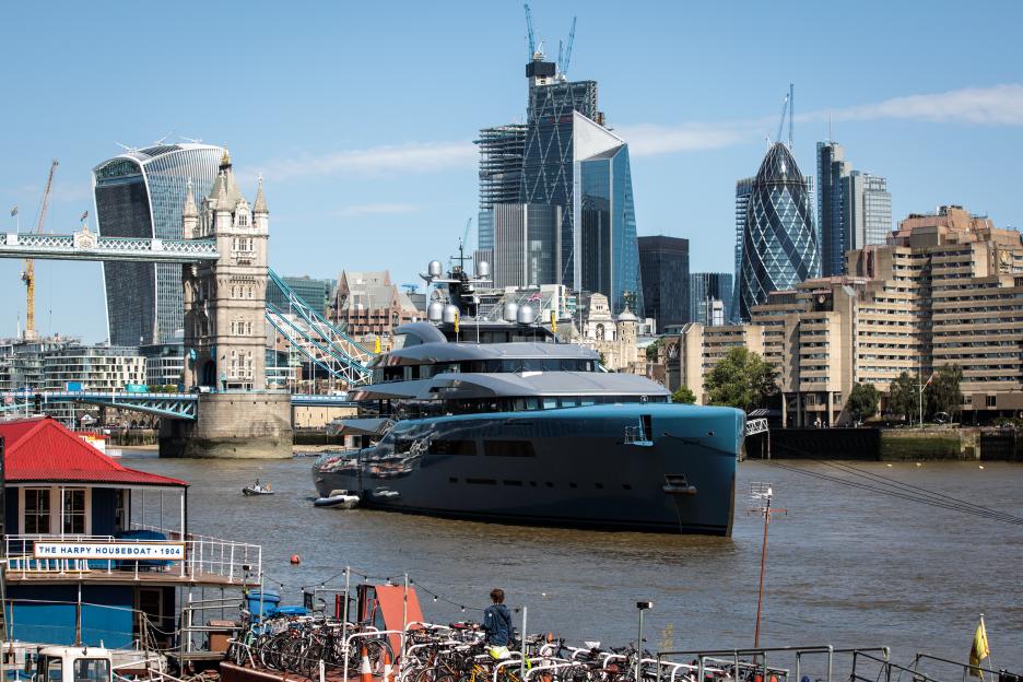 Luxury yacht Aviva moored in London, with Tower Bridge and the city skyline in the background.