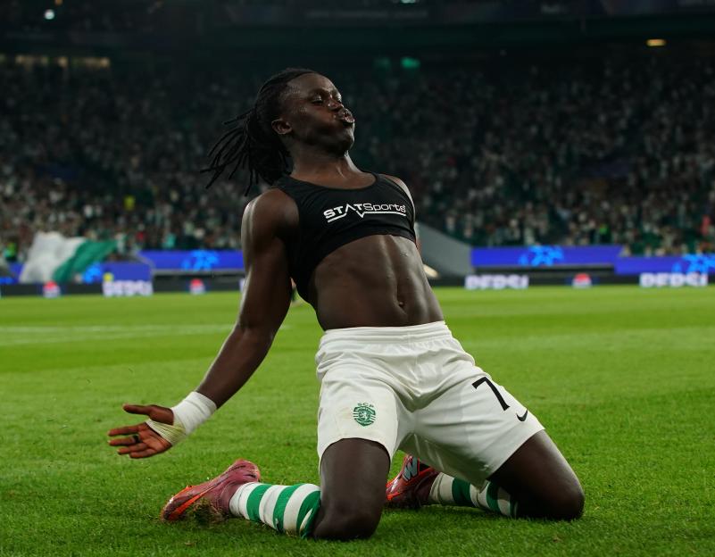 Geovany Quenda of Sporting CP celebrates scoring a goal, kneeling on the grass with his arms outstretched.