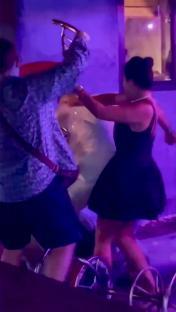 A woman in a black dress holds a suspected laughing gas balloon during a brawl.