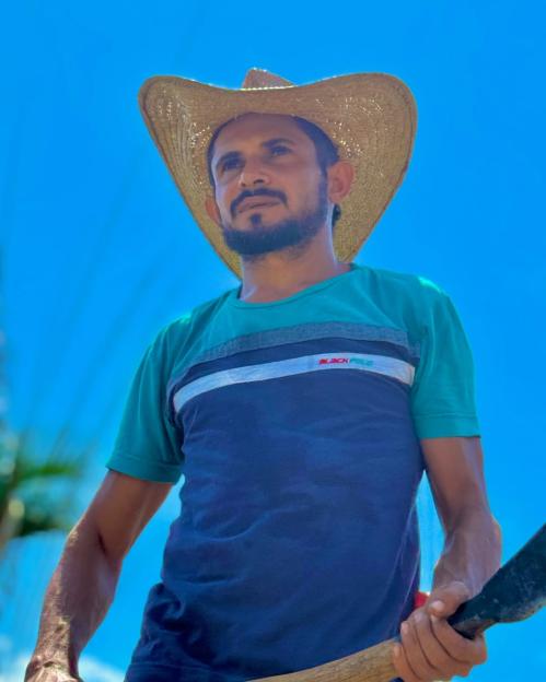 Reinaldo da Silva Melo, an influencer known as "King of Juquira" wearing a straw hat and striped shirt, holding a machete.