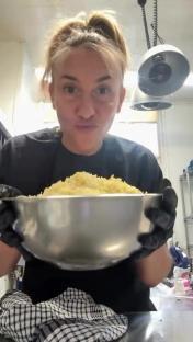 A woman holds a large bowl of food.