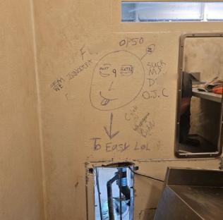 Graffiti on a wall depicting a face and various phrases.