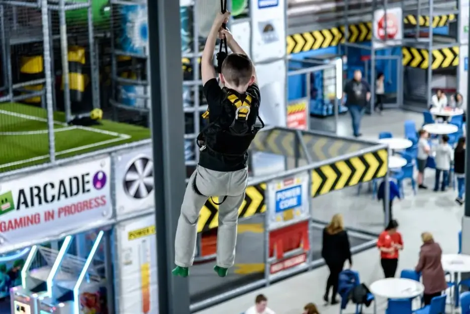A child zip-lining indoors at an adventure park.