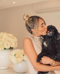 Woman kissing her black dog.