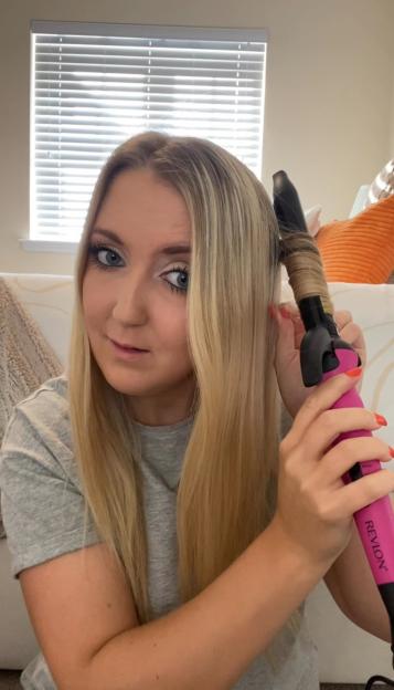 A woman curling her hair with a Revlon curling iron.