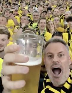 Jamie Carragher with a beer, surrounded by Borussia Dortmund fans.