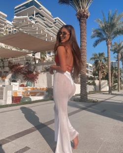 Woman in white pants and red top walking outdoors.