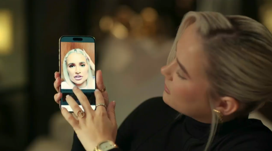 Woman looking at a phone screen showing a selfie.