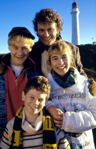 Four actors from Round The Twist smiling at the camera with a lighthouse in the background.