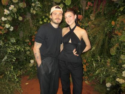 Brooklyn Peltz Beckham and Nicola Peltz Beckham posing together in front of a floral wall.
