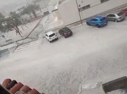 Hail covering cars and a street during a storm.