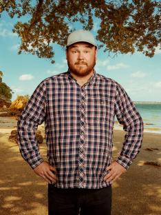 Man in plaid shirt on beach.